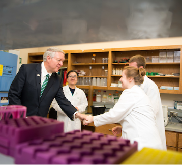 Scientists in laboratory greeted with handshake.