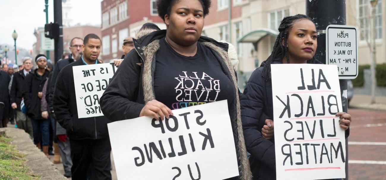 People walk with protest signs in Athens in 2017