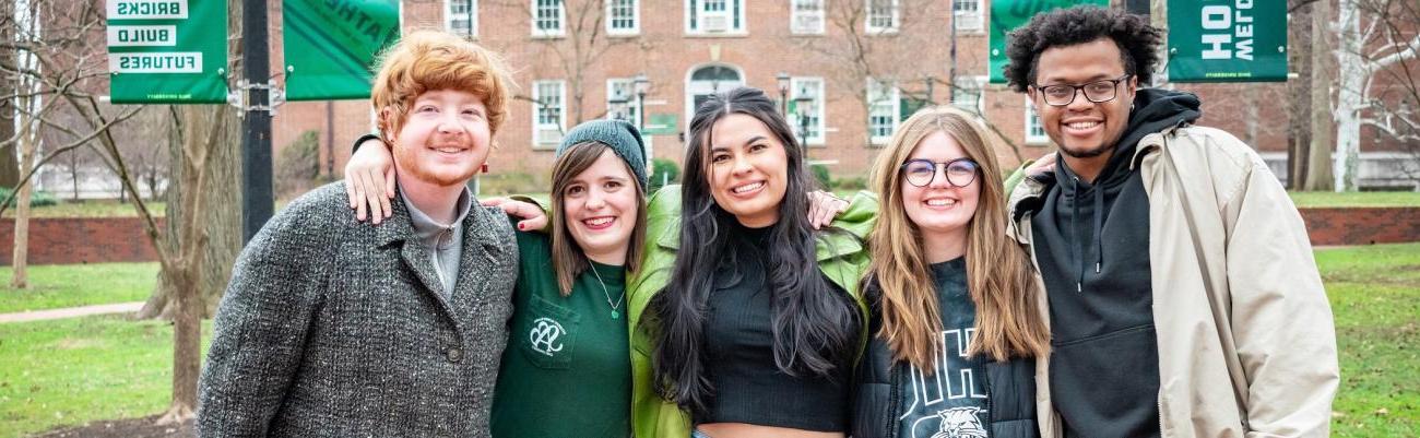 Group of 5 people standing on College Green smiling.